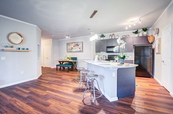 A kitchen with a white island and wooden floors.at Century Ariva, Lakeland, FL 33812  
